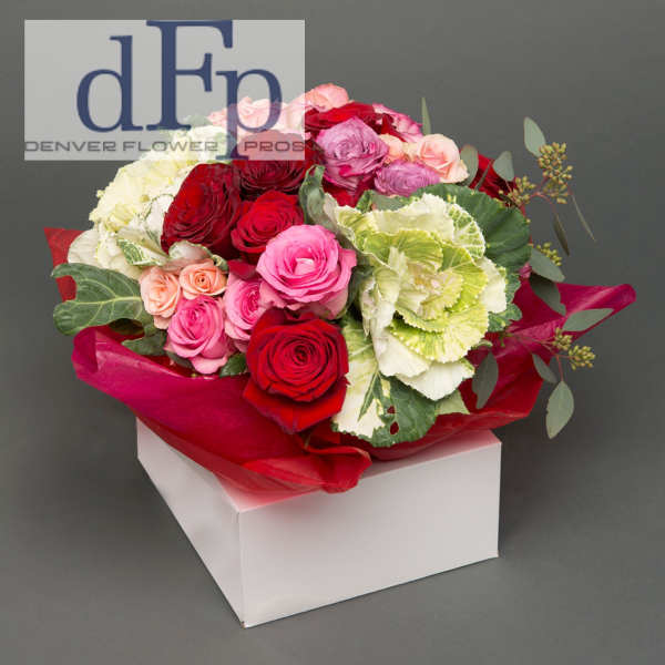 Bouquet of red, pink, and white roses with ornamental cabbage in red wrap