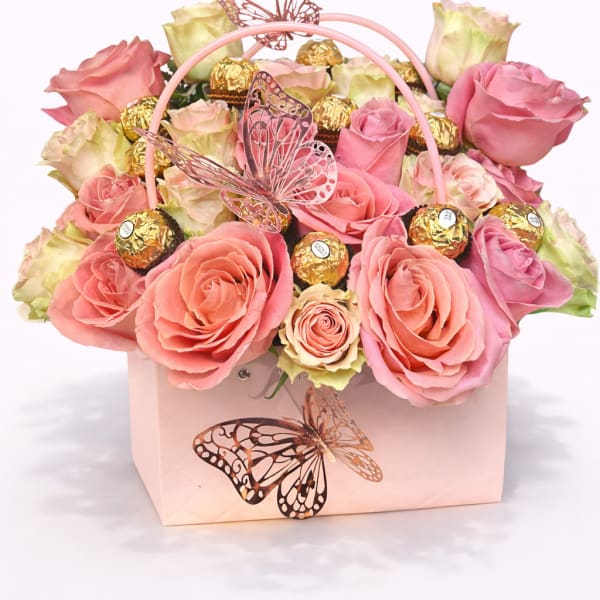 Pink and cream roses in a pale pink gift box with butterfly decorations