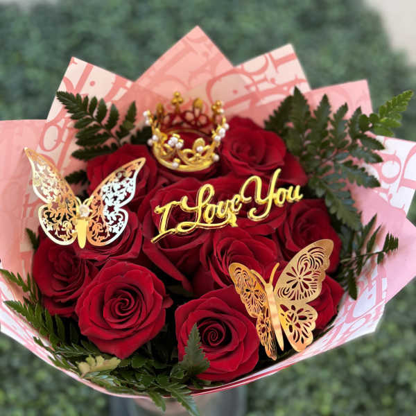 Bouquet of red roses with gold butterfly decorations and a "I Love You" topper