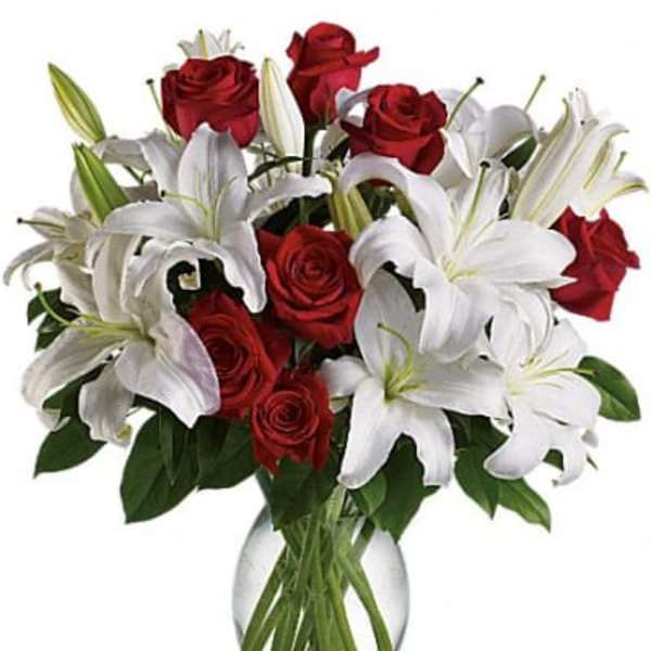 Red roses and white lilies arranged in a clear glass vase