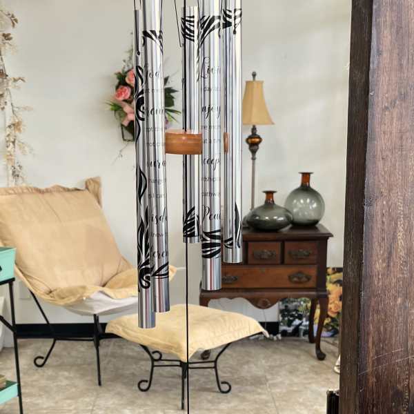 Hanging silver wind chime with black lettering and a round tag