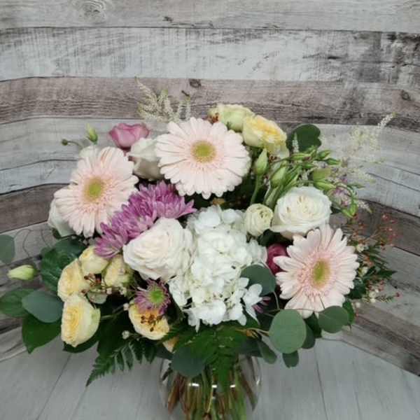 Mixed pastel bouquet in a glass vase with pink daisies and white roses