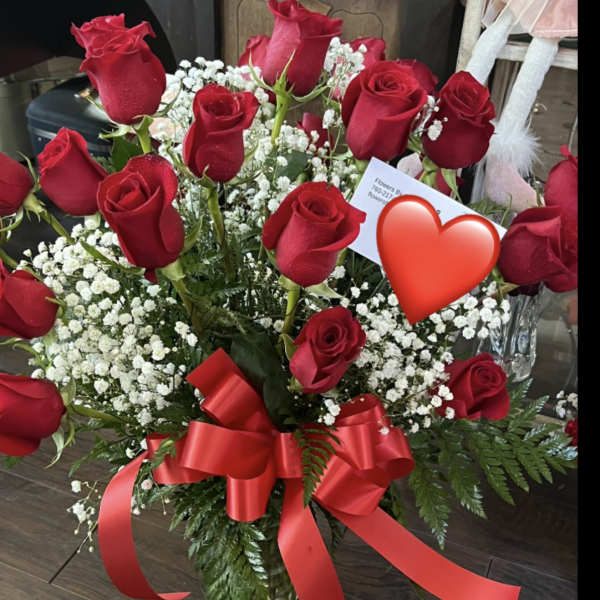 Red roses with baby's breath in a glass vase and red ribbon