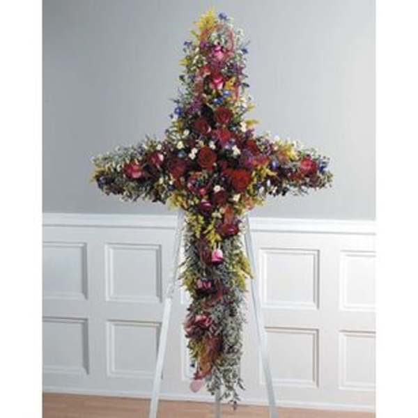 Tall floral cross arrangement on a stand with multicolored flowers