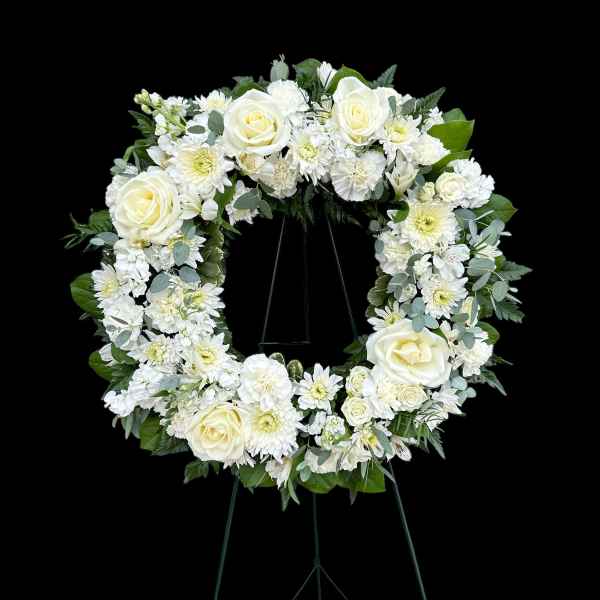 White floral wreath on a black easel stand