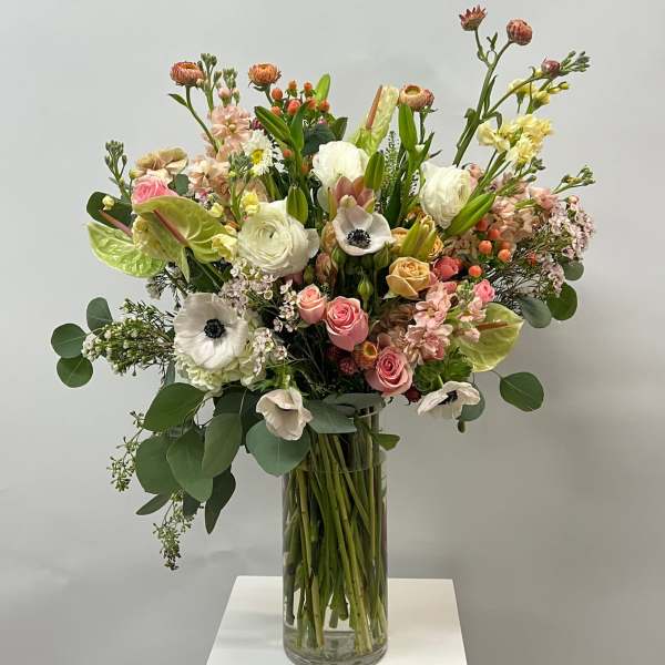 Tall mixed bouquet in a clear glass vase with pink, white, and yellow blooms