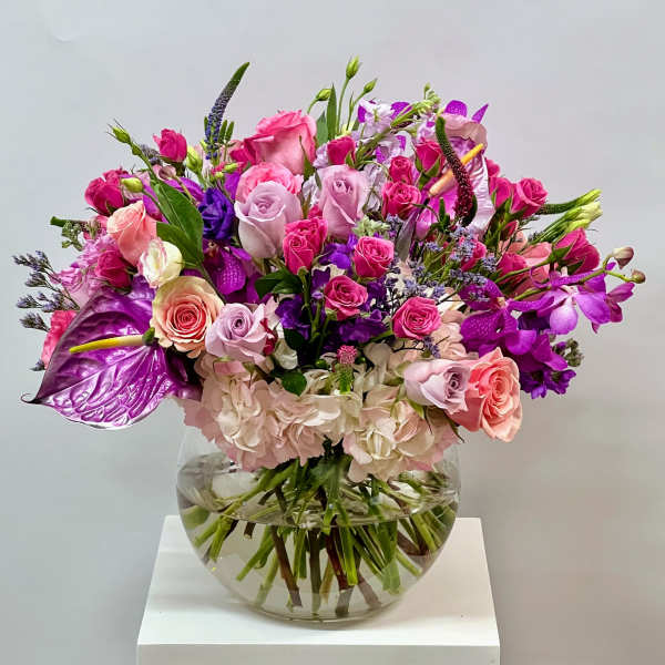 Mixed pink and purple flower arrangement in a clear glass vase