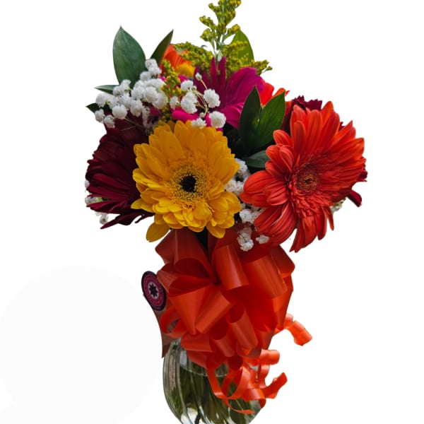 Bouquet of colorful gerbera daisies in a glass vase with an orange ribbon