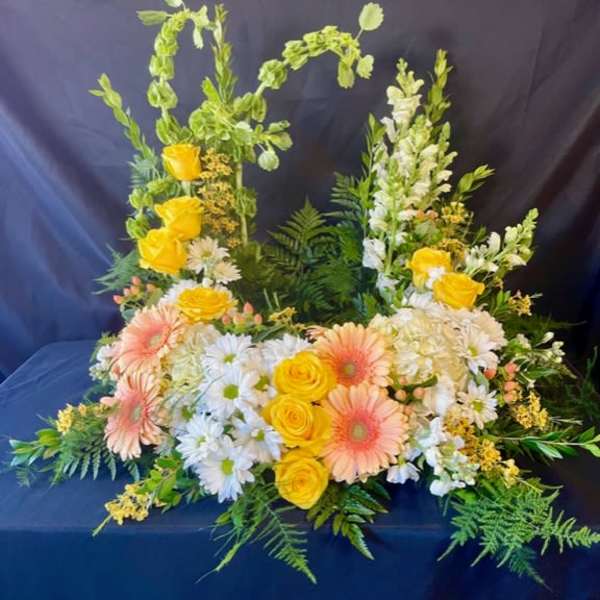 Floral arrangement with yellow roses, peach gerbera daisies, and white daisies