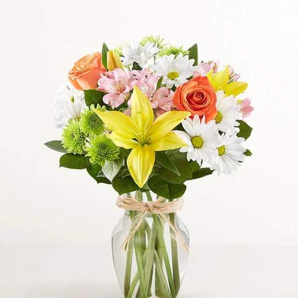 Bouquet of mixed flowers in a clear glass vase with a ribbon