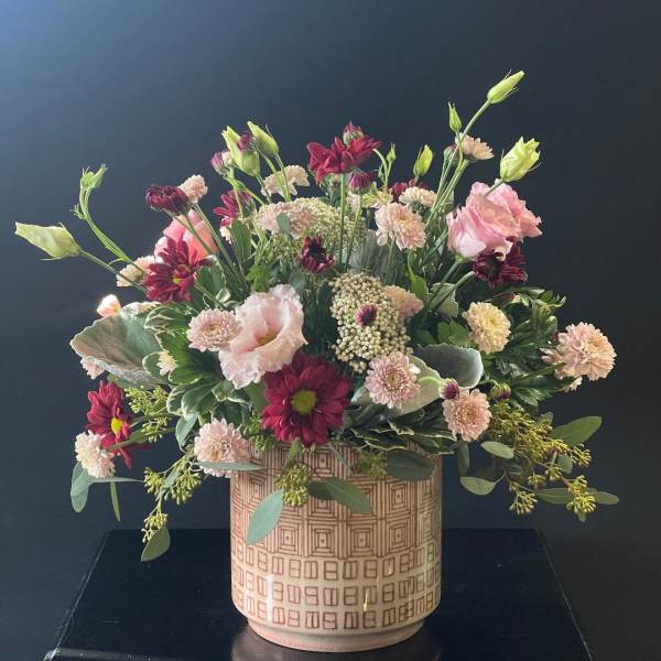 Mixed pink and burgundy flowers in a patterned ceramic vase