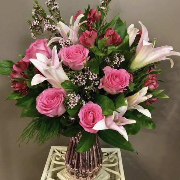 Pink roses and white lilies in a pink glass vase