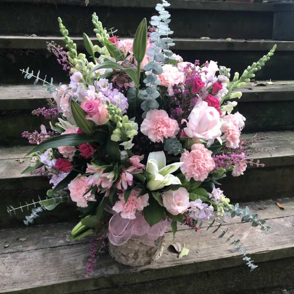 Pink and white mixed flower arrangement in a rustic container