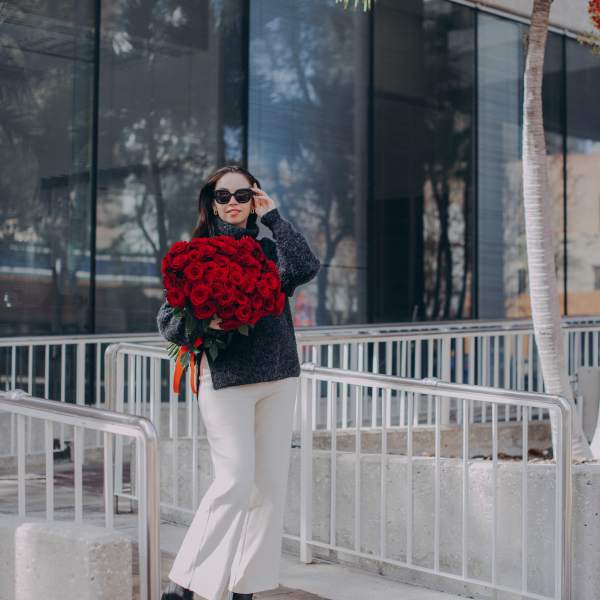 Woman holding a large bouquet of red roses outdoors