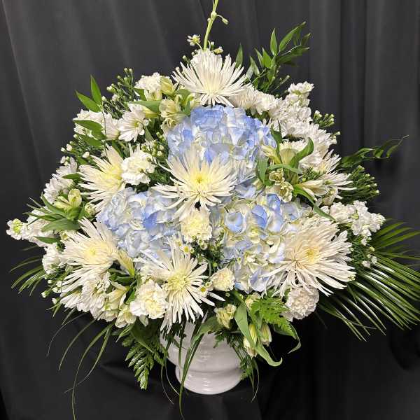 White and pale blue floral arrangement in a white vase