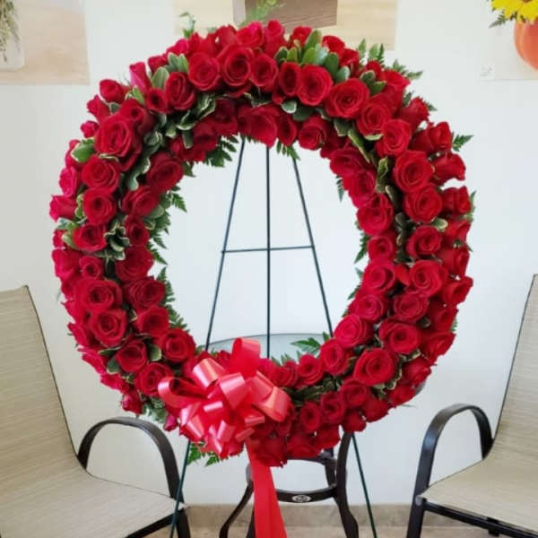 Heart-shaped wreath of red roses on a stand with a red bow