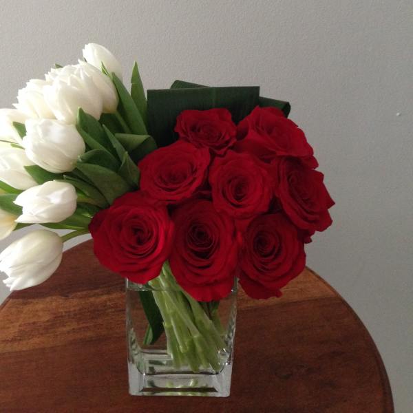 Red roses and white tulips in a clear glass vase