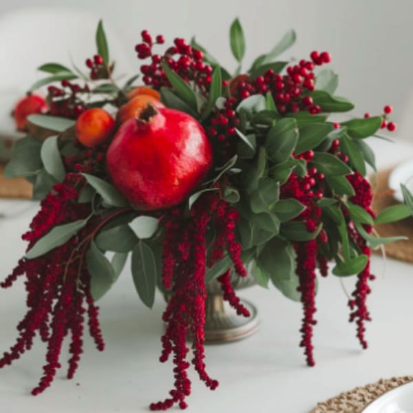 Arrangement with a pomegranate and red berry sprays in a metal vase