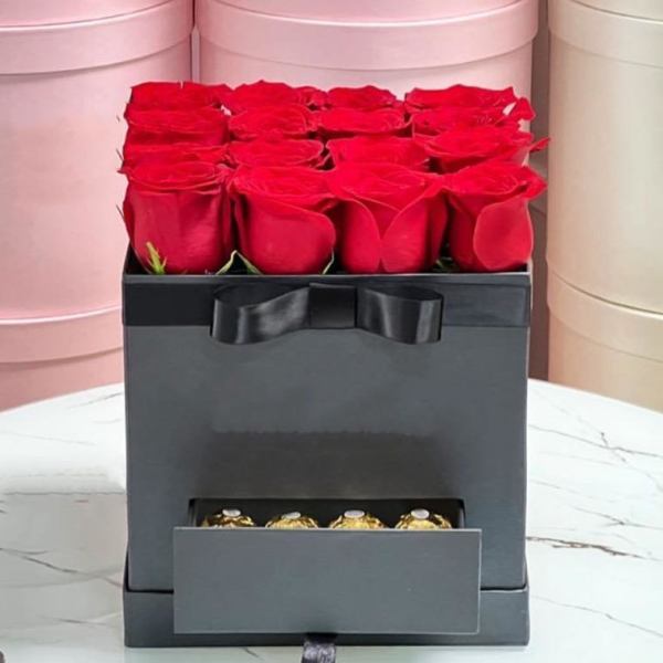 Red roses in a black gift box with a drawer of chocolates