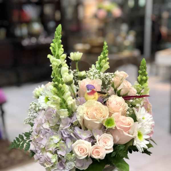 Pastel flower arrangement in a glass vase with roses, hydrangeas, and daisies