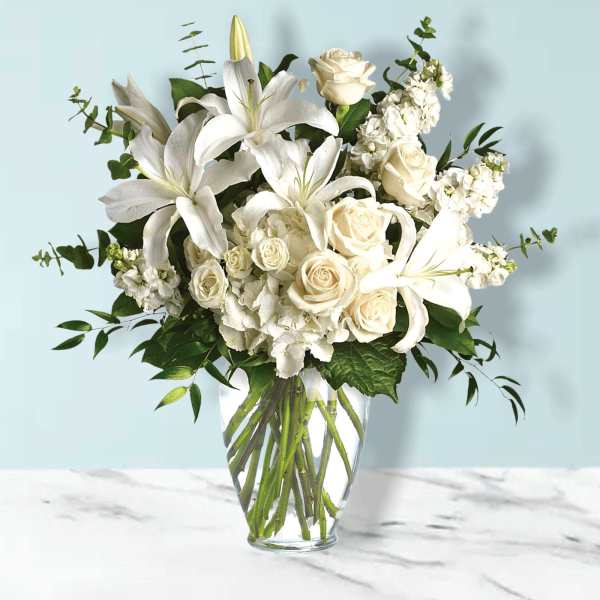 White lilies and roses arranged in a clear glass vase