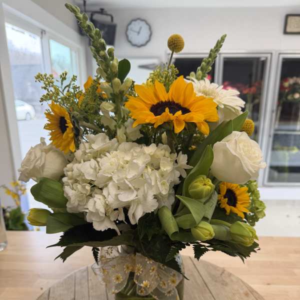 Bouquet of sunflowers, white hydrangea, and white roses in a glass vase
