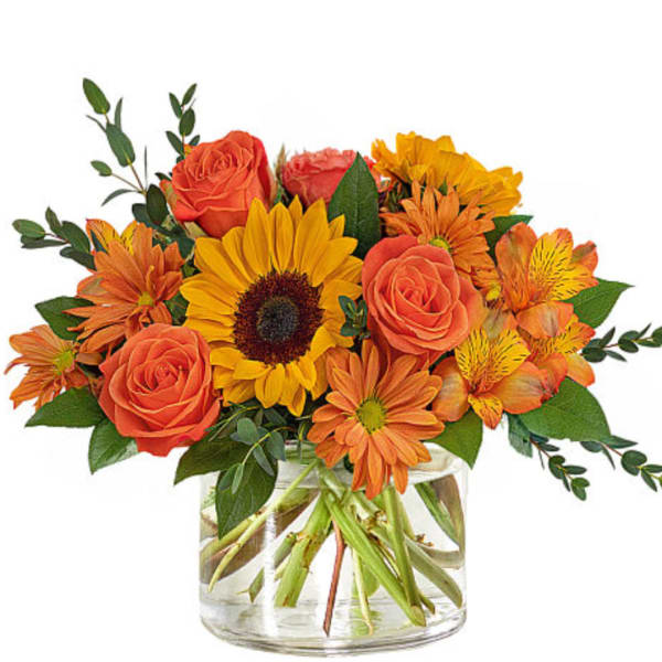 Orange roses and sunflowers in a clear glass vase