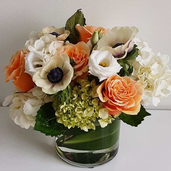 Bouquet of peach, white, and cream flowers in a glass vase