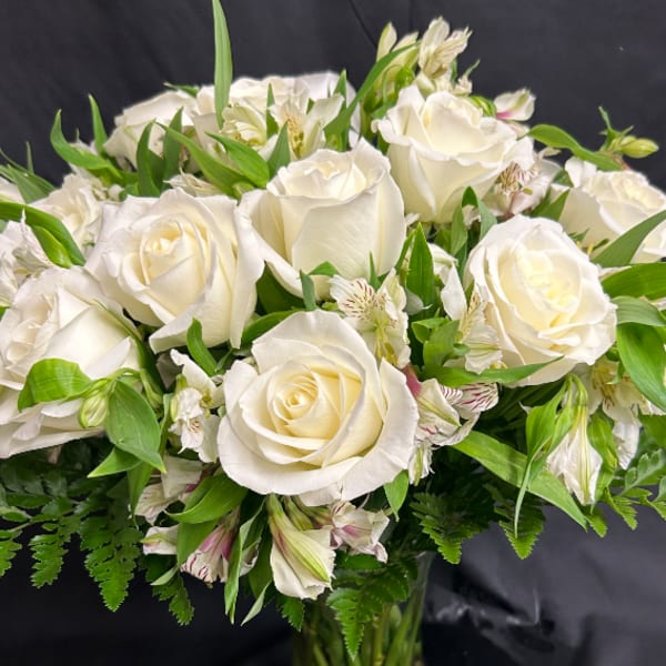 White rose bouquet with green foliage and small striped accent flowers
