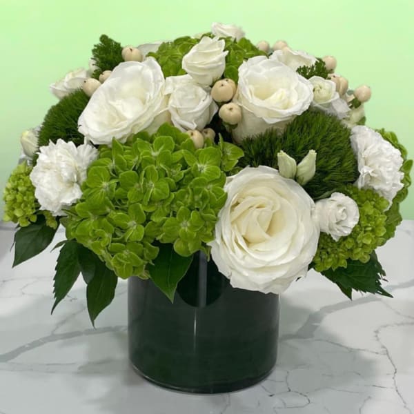 White roses and green hydrangeas arranged in a dark vase