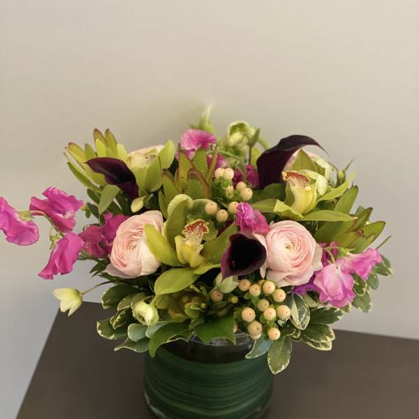 Pink and purple floral arrangement in a green vase