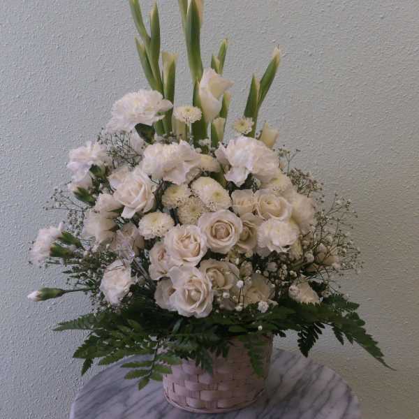 White floral arrangement in a woven basket with tall green stems
