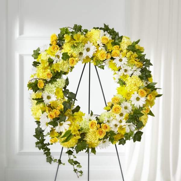 Yellow and white floral wreath on a black stand
