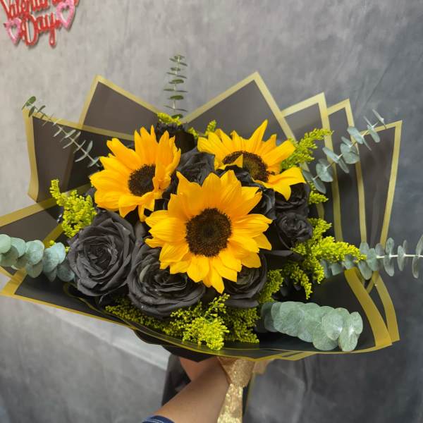Bouquet of yellow sunflowers and black roses wrapped in black paper