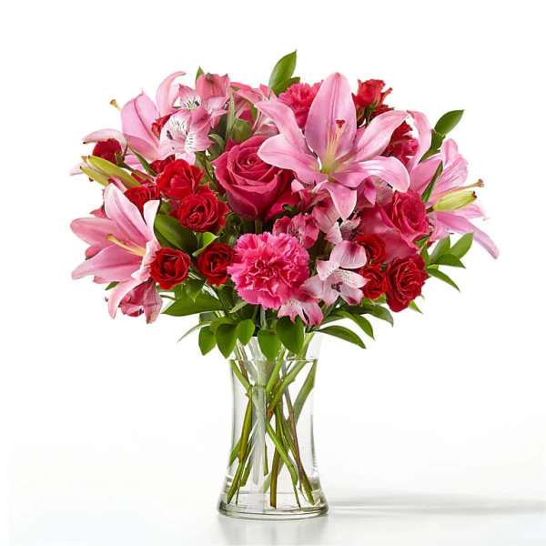Pink lilies, red roses, and carnations in a clear glass vase