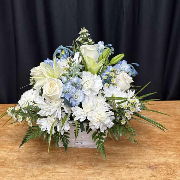 White and pale blue floral arrangement in a white basket