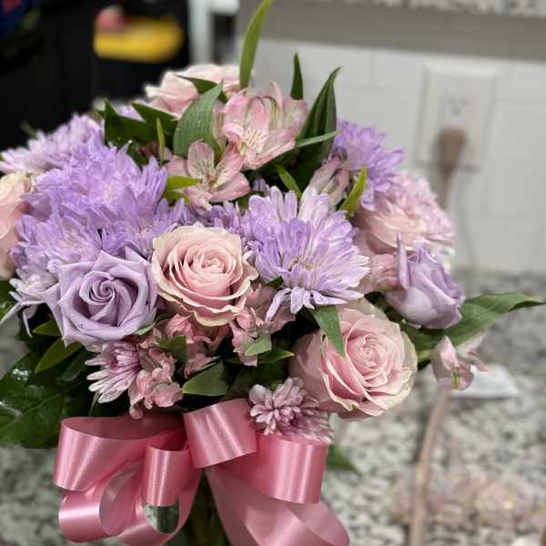 Pink and lavender bouquet with roses and daisies tied with a pink ribbon
