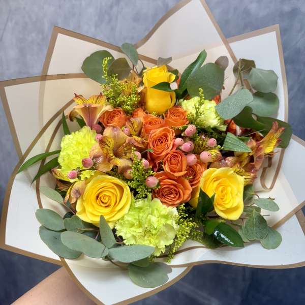 Bouquet of yellow and orange roses with green and pink accents