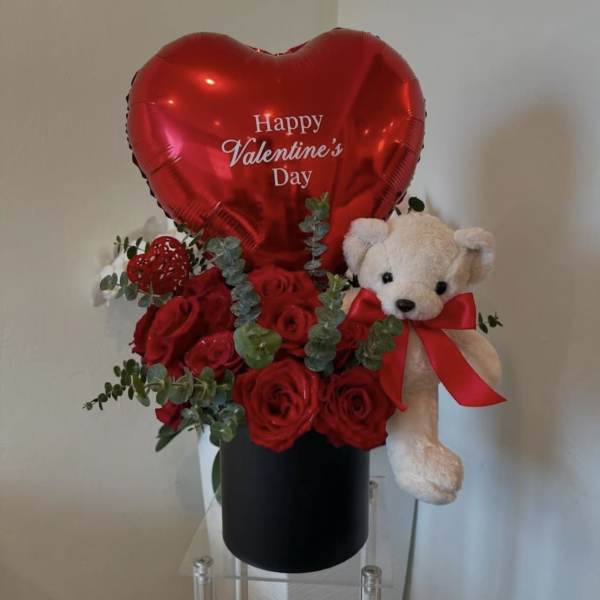 Red rose arrangement with a heart balloon and teddy bear in a black box