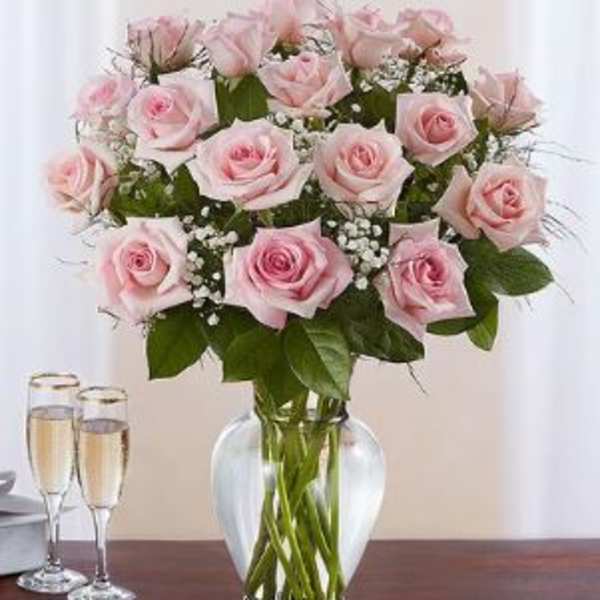 Pink roses arranged in a clear glass vase with baby's breath