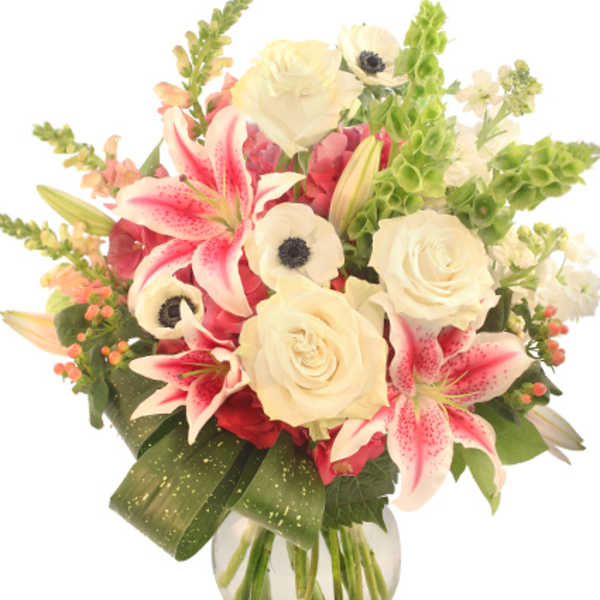 Bouquet of white roses, pink lilies, and white anemones in a glass vase