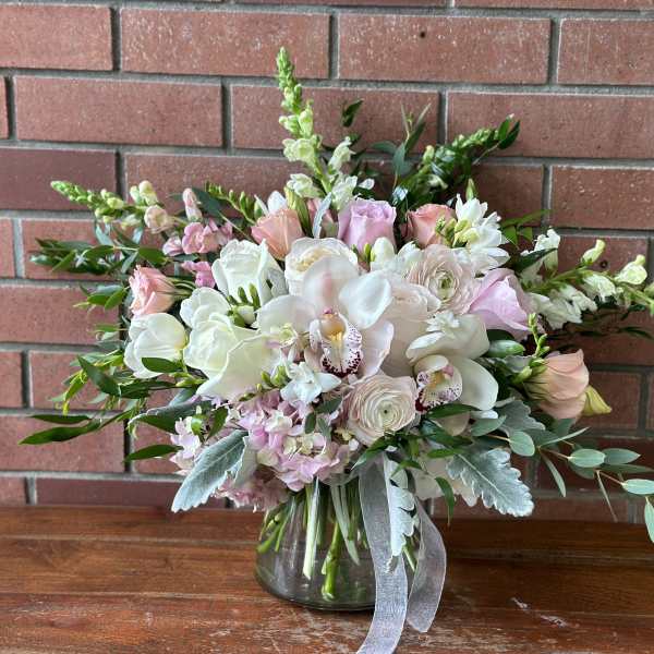 Pink and white bouquet in a glass vase with trailing greenery