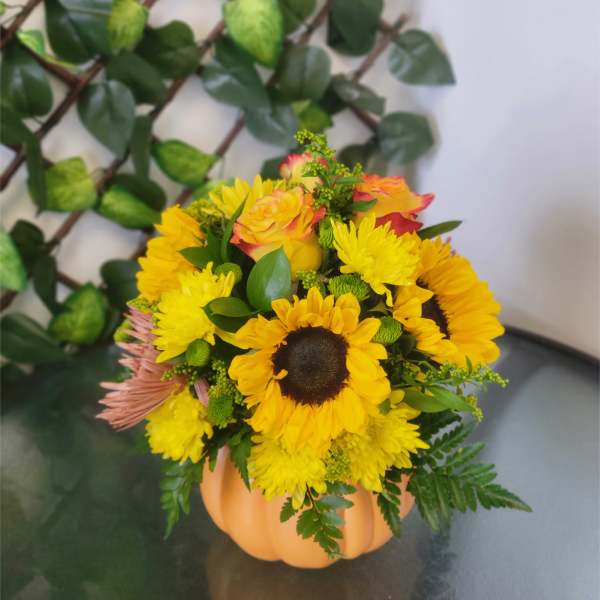Sunflower and yellow chrysanthemum arrangement in a pumpkin-shaped vase