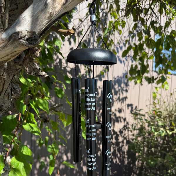 Black memorial wind chime hanging outdoors from a tree