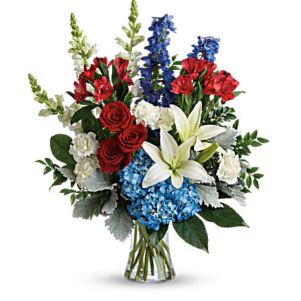 Bouquet of red roses, white lilies, blue flowers, and red blooms in a glass vase