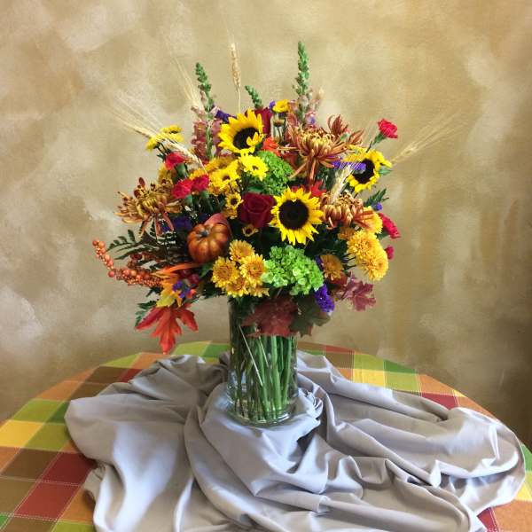 Mixed bouquet with sunflowers, roses, and chrysanthemums in a glass vase