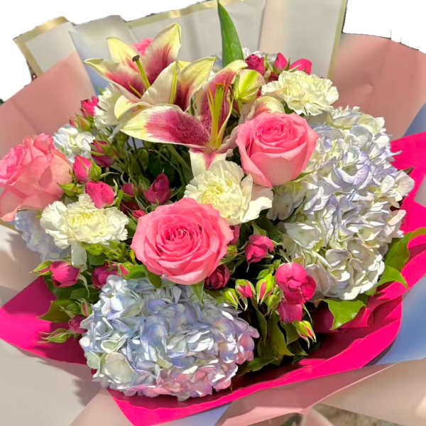 Bouquet of pink roses, lilies, and hydrangeas wrapped in pink paper