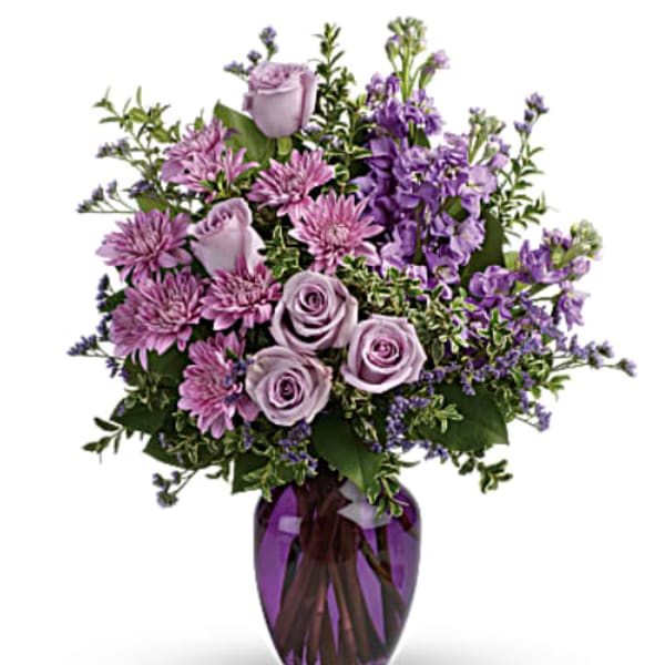 Lavender roses and purple flowers in a purple glass vase