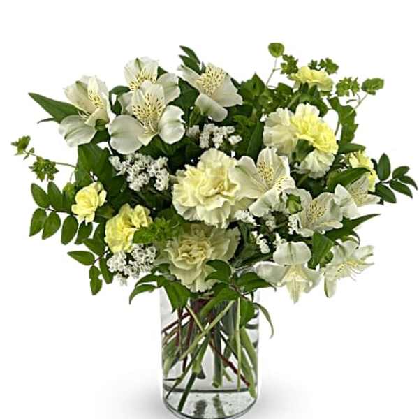 White and pale yellow flowers arranged in a clear glass vase