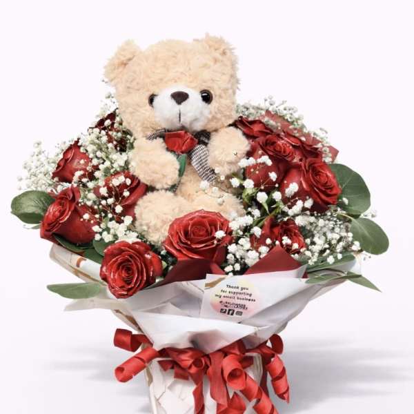 Teddy bear surrounded by red roses in a wrapped bouquet